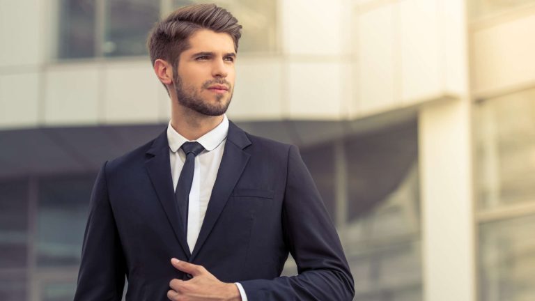 Young businessman in suit outdoors, looking confident.