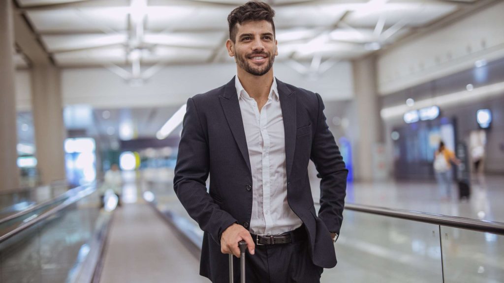 Smiling businessman at airport with suitcase