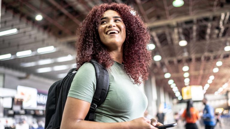 Happy woman with phone in busy indoor setting.