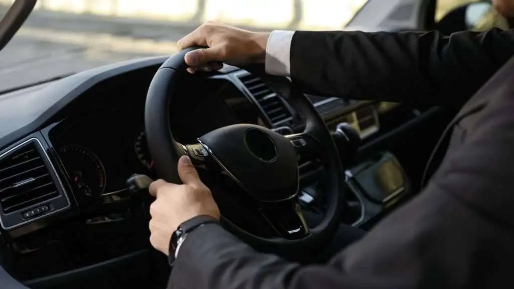 Businessman driving modern car, hands on steering wheel