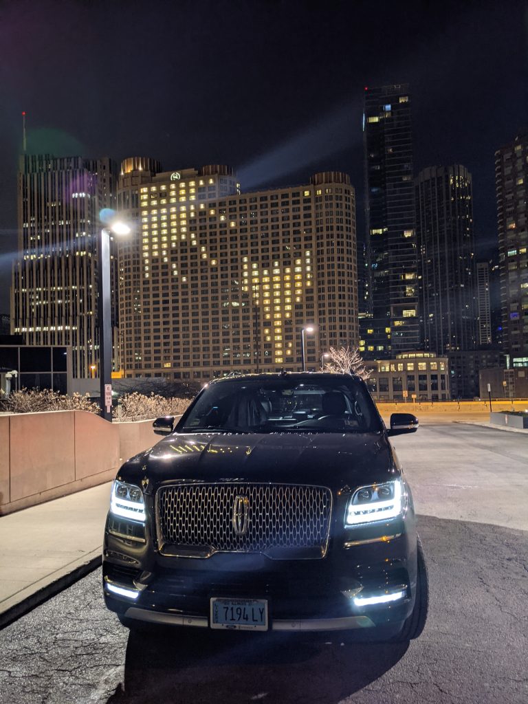 Luxury car parked at night with illuminated cityscape