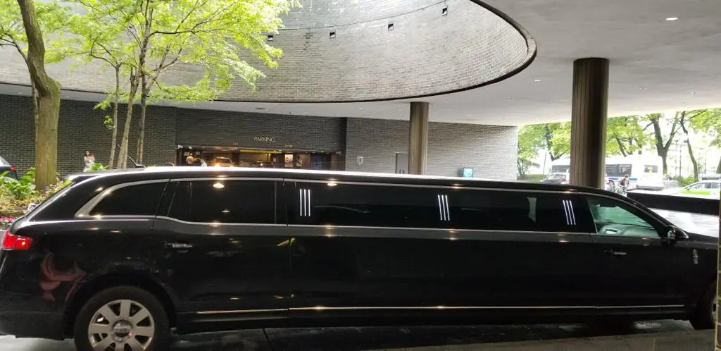 Black limousine parked under modern building canopy