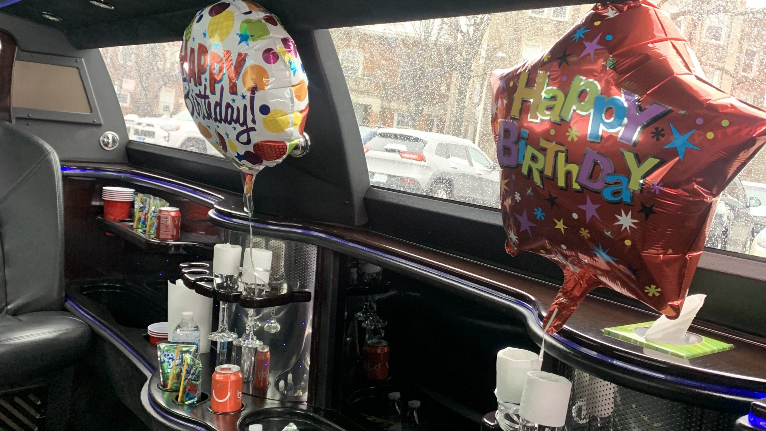 Decorated limousine interior with birthday balloons and drinks