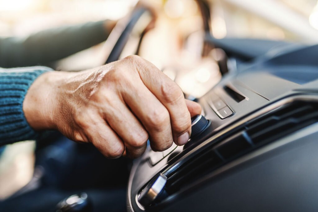 Can I Play My Own Music in a Limousine? - Hand adjusting car stereo knob