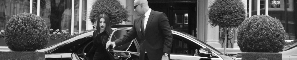Difference Between a Chauffeur and a Driver - Chauffeur helps woman exit luxury car in front of hotel.