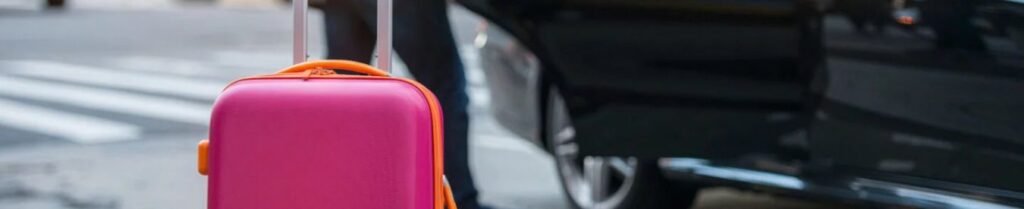 Is An Airport Car Service Worth It? - Pink suitcase beside open car door on street.