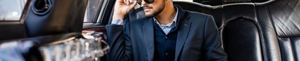 What is Proper Limousine Etiquette? - Man in suit and sunglasses inside a car.