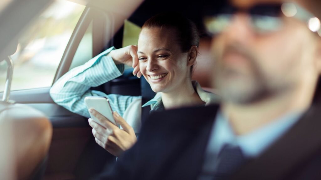 Smiling woman using smartphone in car