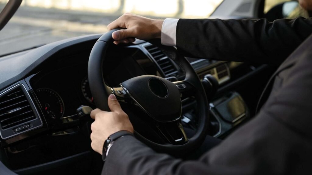Person driving a car with focus on steering wheel.