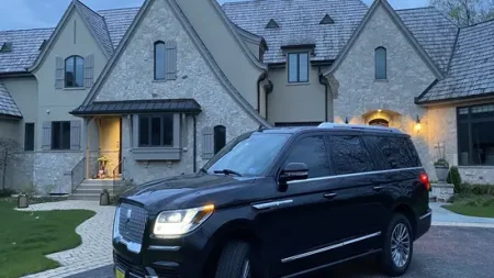 Black SUV parked in front of large house